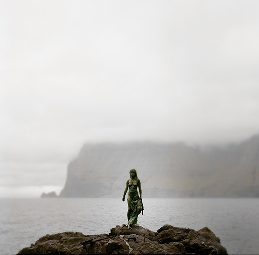 
			<br /><em>The Legend of the Selkie, Seal Woman
			<br /><br /><br /><br />| Kalsoy Island
			<br /><br /><br />Mikladalur has a legend of a selkie. 
			<br />Seals were believed to be former humans who 
			<br />voluntarily sought death in the ocean. 
			<br />Once a year, on Twelfth Night, they were allowed 
			<br />to come on land, strip off their skins and amuse themselves 
			<br />as human beings, dancing and enjoying themselves.
			<br /><br />A young farmer from Mikladalur once went to 
			<br />the beach to watch the selkies dance. 
			<br />There he sees a beautiful selkie maiden shedding 
			<br />her seal skin, and he is hit by an intense desire for her. 
			<br />He hides the skin, so that she cannot go back to sea 
			<br />at the end of the night, and confronts her, 
			<br />and forces her to marry him. 
			<br />The man kept her skin in a chest, and
			<br />kept the key with him both day and night. 
			<br />Like this they lived for several years, 
			<br />having several children together. 
			<br />One day when out fishing, he discovers 
			<br />that he has forgotten to bring his key, 
			<br />and rows back home with his power. 
			<br />When he returns home, his wife has escaped
			<br />back to sea, leaving their children behind, 
			<br />but has put out the fire and hid away any 
			<br />sharp objects, so that they wouldn't be harmed.
			<br /><br />Then one day it happened that the Mikladalur 
			<br />men planned to go deep into one of the caverns along 
			<br />the far coast to hunt the seals that lived there. 
			<br />The night before they were due to go, 
			<br />the man’s seal wife appeared to him in a dream 
			<br />and said that if he went on the seal hunt in the cavern, 
			<br />he should make sure he didn’t kill the great bull seal 
			<br />that would be lying at the entrance, for that was her husband. 
			<br />Nor should he harm the two seal pups deep inside 
			<br />the cave, for they were her two young sons, 
			<br />and she described their skins so he would know them. 
			<br />But the farmer didn’t heed the dream message. 
			<br />He joined the others on the hunt, and they killed 
			<br />all the seals they could lay their hands on. 
			<br />When they got back home, the catch was divided up, 
			<br />and for his share the farmer received the large bull seal 
			<br />and both the front and the hind flippers of the two young pups.
			<br /><br />In the evening, when the head of the large seal 
			<br />and the limbs of the small ones had been cooked for dinner, 
			<br />there was a great crash in the smoke-room, 
			<br />and the seal woman appeared in the form of a terrifying troll; 
			<br />she sniffed at the food in the troughs and cried the curse: 
			<br />‘Here lie the head of my husband with his broad nostrils, 
			<br />the hand of Hárek and the foot of Fredrik! 
			<br />Now there shall be revenge, revenge on the men of Mikladalur, 
			<br />and some will die at sea and others fall from the mountain tops, 
			<br />until there be as many dead as can link hands all 
			<br />round the shores of the isle of Kalsoy!’
			<br /><br />When she had pronounced these words, 
			<br />she vanished with a great crash of thunder and was never seen again. 
			<br />But still today, alas, it so happens from time to time that men 
			<br />from the village of Mikladalur get drowned at sea or fall from the tops of cliffs; 
			<br />it must therefore be feared that the number of victims is not yet great enough 
			<br />for all the dead to link hands around the whole island of Kalsoy.
			<br />There stands a statue of the selkie, down at the shore
			<br />amidst the crashing surf in Mikladalur.
			<br /></em>
